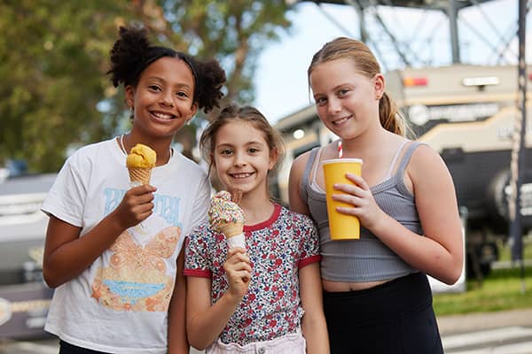 Three smiling children with ice-creams and milkshakes.