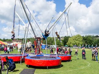 Group of children on a bungee trampoline with spectators watching